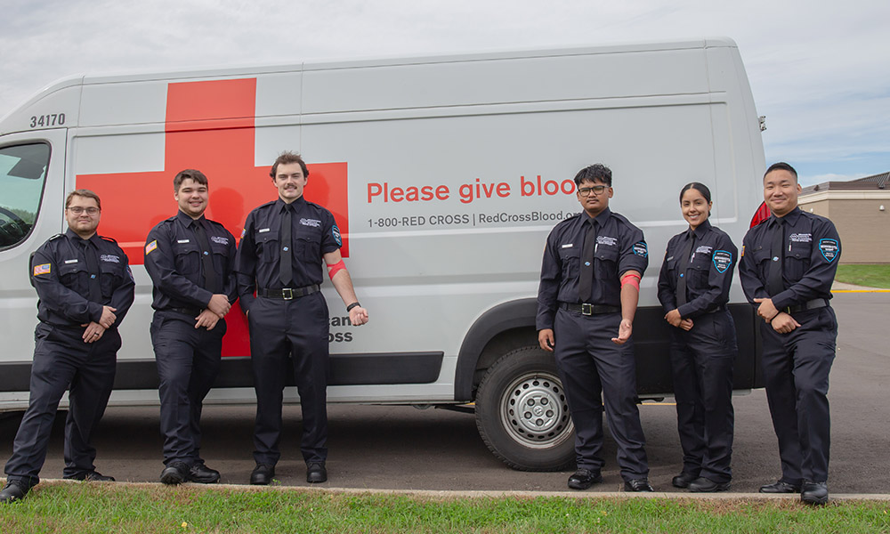 Peace Officer Students near Red Cross Blood van smiling at event